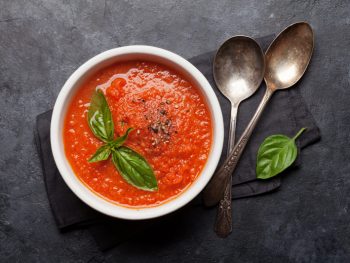 Delicious tomato soup in a white bowl with fresh parsley on top