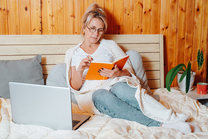 Woman writes in her journal as she lays in bed after hysterectomy.