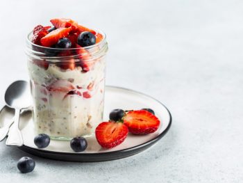 Tasty-looking overnight oats in a cup with straberries and blueberries