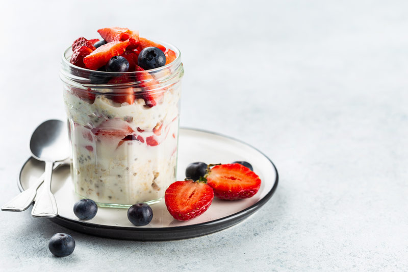 Tasty-looking overnight oats in a cup with straberries and blueberries