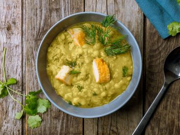 Tasty split pea soup in a gray bowl, sprinkled with fresh parsley