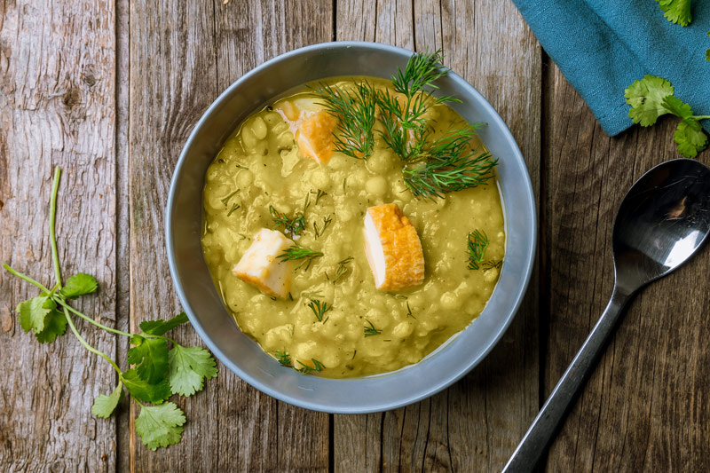 Tasty split pea soup in a gray bowl, sprinkled with fresh parsley