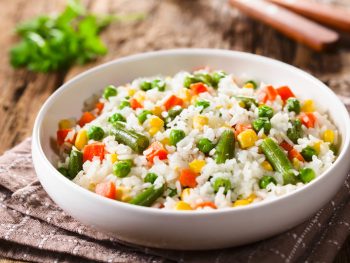 White rice with carrots, peas and veggies cooked to perfection on a plate