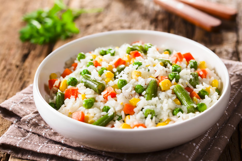 White rice with carrots, peas and veggies cooked to perfection on a plate