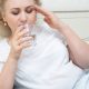 Woman drinks water as she tries to cool down from a hot flash