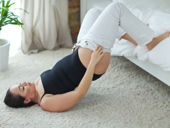 Woman struggling to get into her jeans after hysterectomy surgery